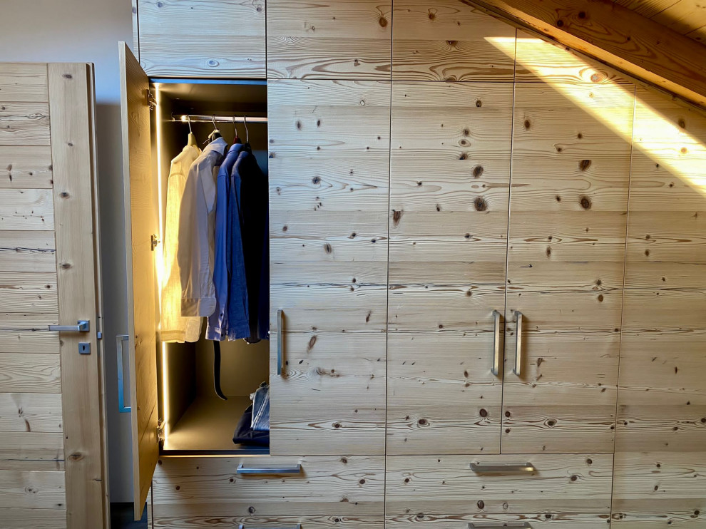 Diseño de armario unisex actual grande con armarios con paneles lisos, puertas de armario de madera clara y vigas vistas