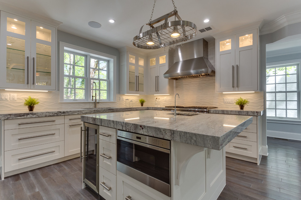 Example of a large transitional l-shaped medium tone wood floor open concept kitchen design in DC Metro with a single-bowl sink, shaker cabinets, white cabinets, marble countertops, white backsplash, porcelain backsplash, stainless steel appliances and an island