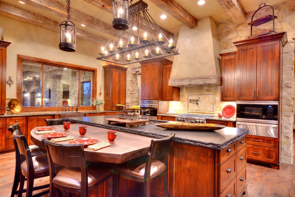 Eat-in kitchen - rustic u-shaped medium tone wood floor eat-in kitchen idea in Austin with a farmhouse sink, beaded inset cabinets, medium tone wood cabinets, granite countertops, stainless steel appliances and an island