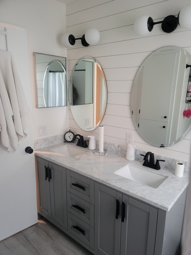 Small cottage master vinyl floor, gray floor and double-sink alcove bathtub photo in Other with shaker cabinets, gray cabinets, a two-piece toilet, white walls, an undermount sink, marble countertops, white countertops and a freestanding vanity