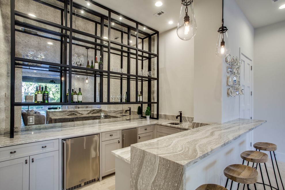 This is an example of a mid-sized transitional u-shaped seated home bar in Dallas with an undermount sink, shaker cabinets, white cabinets, mirror splashback, travertine floors, brown floor and grey benchtop.