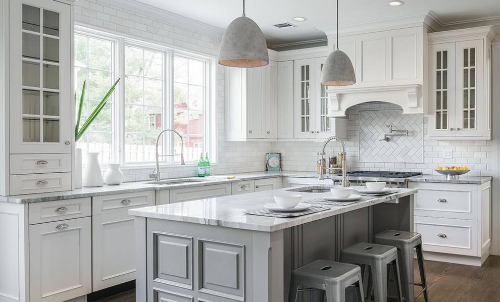 Photo of a large traditional l-shaped kitchen in New York with an undermount sink, white cabinets, white splashback, subway tile splashback, dark hardwood floors, with island, brown floor, grey benchtop and recessed-panel cabinets.