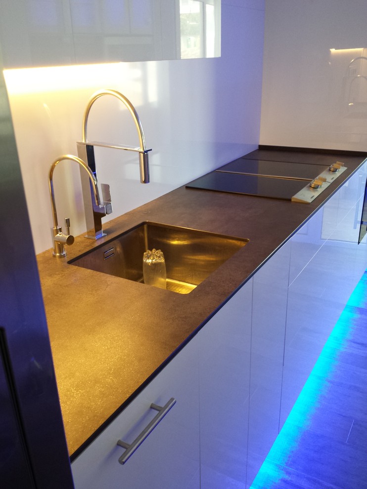 Photo of a mid-sized modern single-wall open plan kitchen in Other with an undermount sink, flat-panel cabinets, white cabinets, quartz benchtops, white splashback, mirror splashback, stainless steel appliances, porcelain floors and a peninsula.