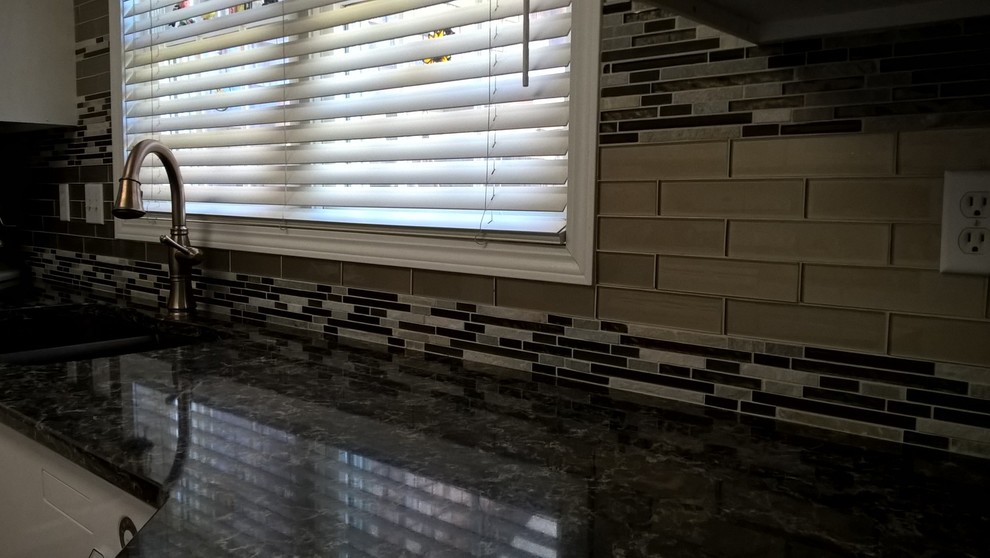 Kitchen - transitional kitchen idea with a double-bowl sink, raised-panel cabinets, white cabinets, granite countertops, multicolored backsplash, glass tile backsplash and stainless steel appliances