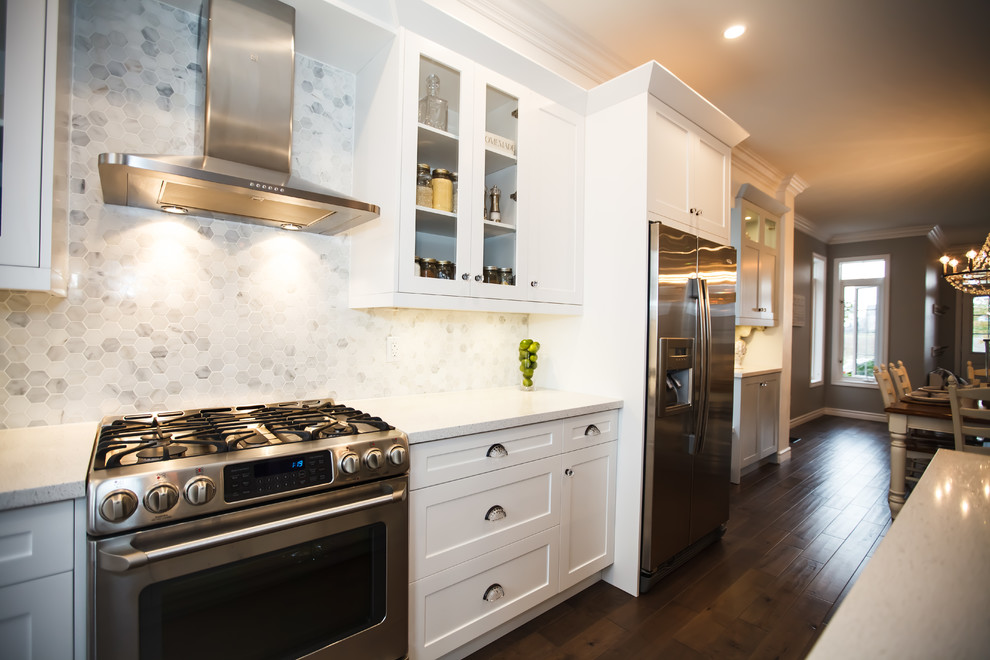 Example of a mid-sized transitional galley dark wood floor eat-in kitchen design in Toronto with an undermount sink, shaker cabinets, white cabinets, granite countertops, white backsplash, stone tile backsplash, stainless steel appliances and an island