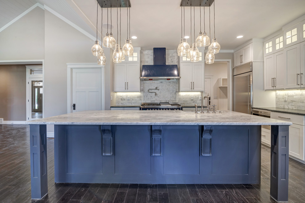 Large transitional l-shaped open plan kitchen in Salt Lake City with a farmhouse sink, shaker cabinets, white cabinets, marble benchtops, white splashback, marble splashback, stainless steel appliances, dark hardwood floors, with island, brown floor and white benchtop.