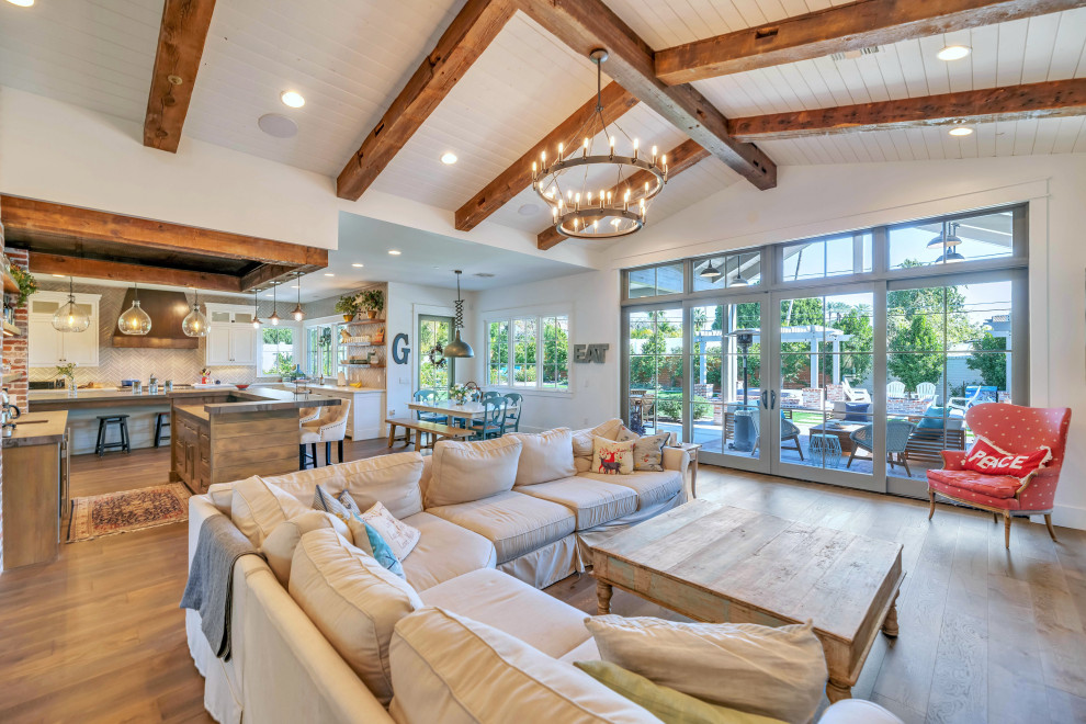 This is an example of a country open concept living room in Phoenix with white walls, medium hardwood floors, brown floor and exposed beam.