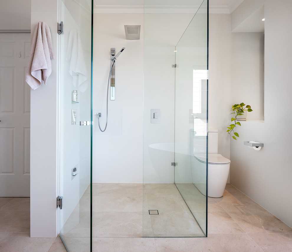This is an example of a large contemporary master bathroom in Perth with a freestanding tub, an open shower, porcelain tile, beige walls, marble floors, a wall-mount sink, marble benchtops, beige floor, a hinged shower door and white benchtops.