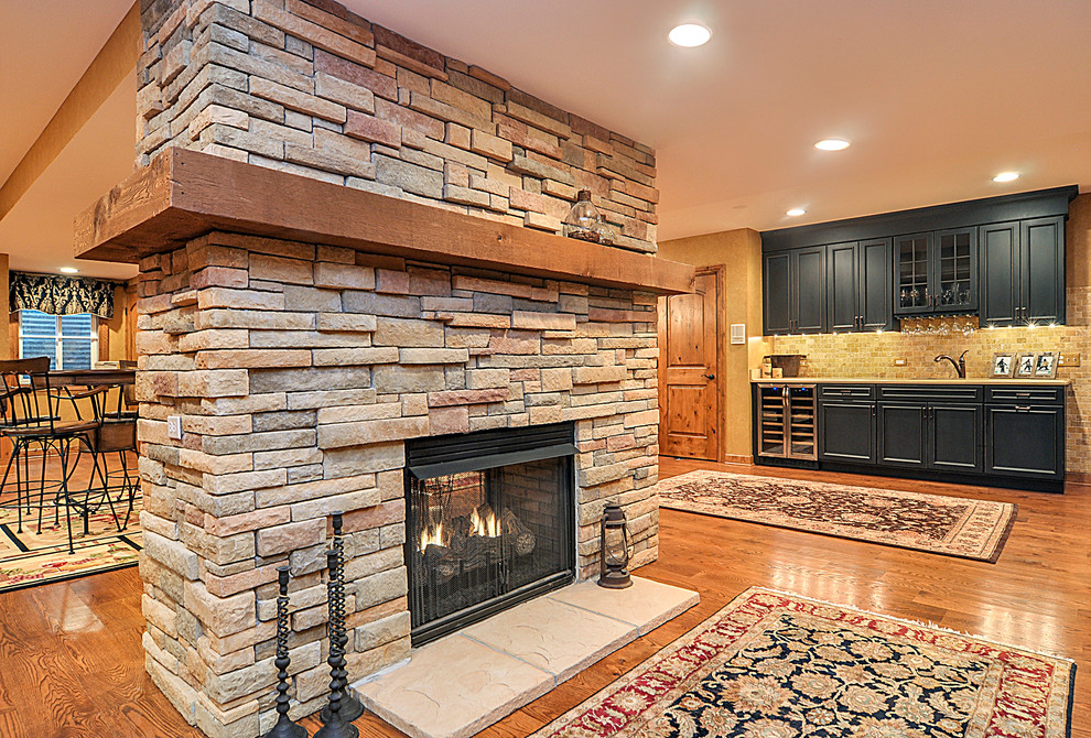 Design ideas for a large country fully buried basement in Nashville with beige walls, medium hardwood floors, a two-sided fireplace and a stone fireplace surround.