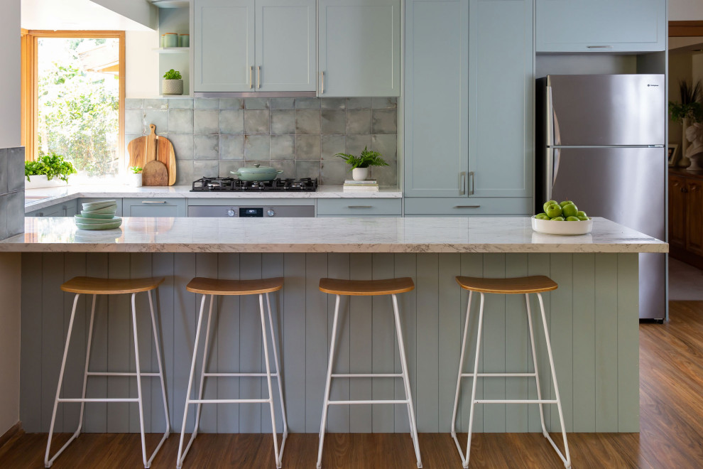 Large traditional u-shaped kitchen pantry in Melbourne with a drop-in sink, shaker cabinets, green cabinets, laminate benchtops, green splashback, porcelain splashback, stainless steel appliances, dark hardwood floors, with island and grey benchtop.
