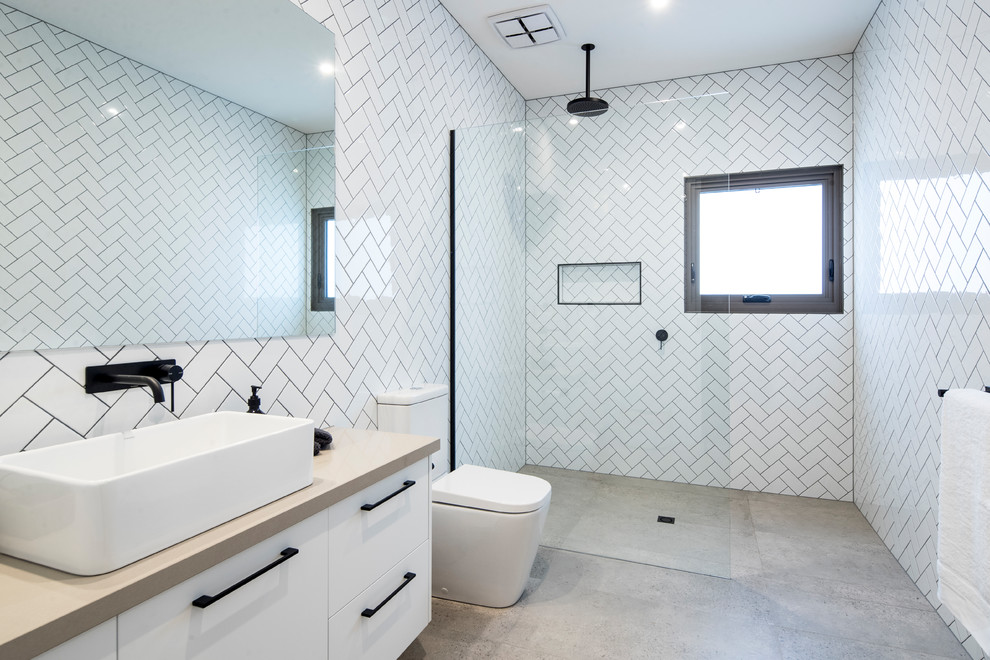 This is an example of a contemporary 3/4 bathroom in Geelong with flat-panel cabinets, white cabinets, an open shower, white tile, ceramic tile, white walls, a vessel sink, engineered quartz benchtops, an open shower, grey floor and grey benchtops.