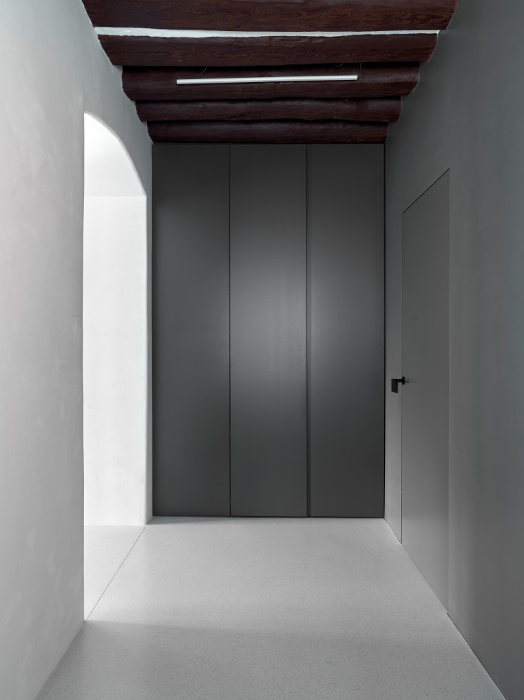 Photo of a mid-sized contemporary foyer in Other with white walls, terrazzo floors, a single front door, a white front door, grey floor and exposed beam.
