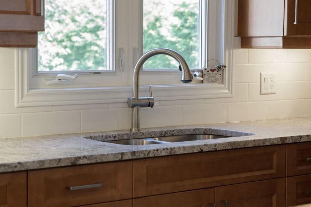 Inspiration for a contemporary porcelain tile eat-in kitchen remodel with an undermount sink, shaker cabinets, medium tone wood cabinets, granite countertops, white backsplash, porcelain backsplash, stainless steel appliances and an island