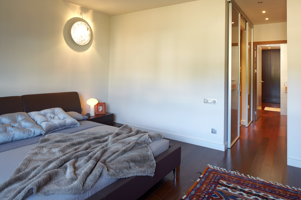 Ejemplo de dormitorio principal contemporáneo de tamaño medio sin chimenea con paredes blancas y suelo de madera oscura