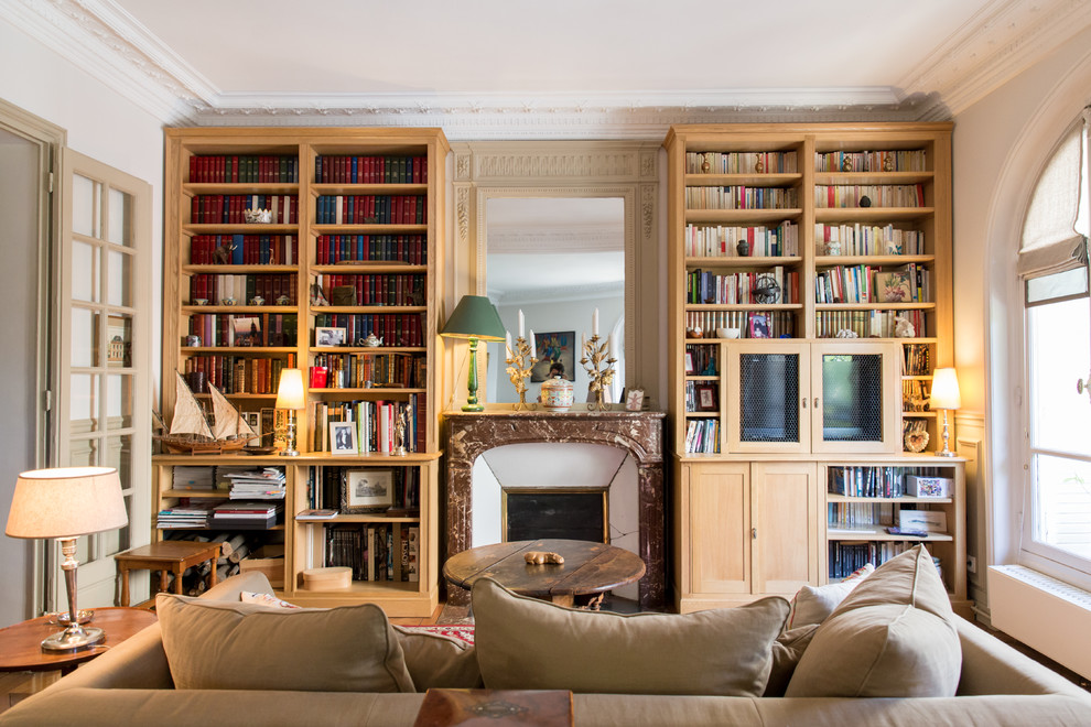 This is an example of a mid-sized traditional enclosed family room in Paris with a library, white walls, medium hardwood floors, a standard fireplace, a stone fireplace surround and a concealed tv.