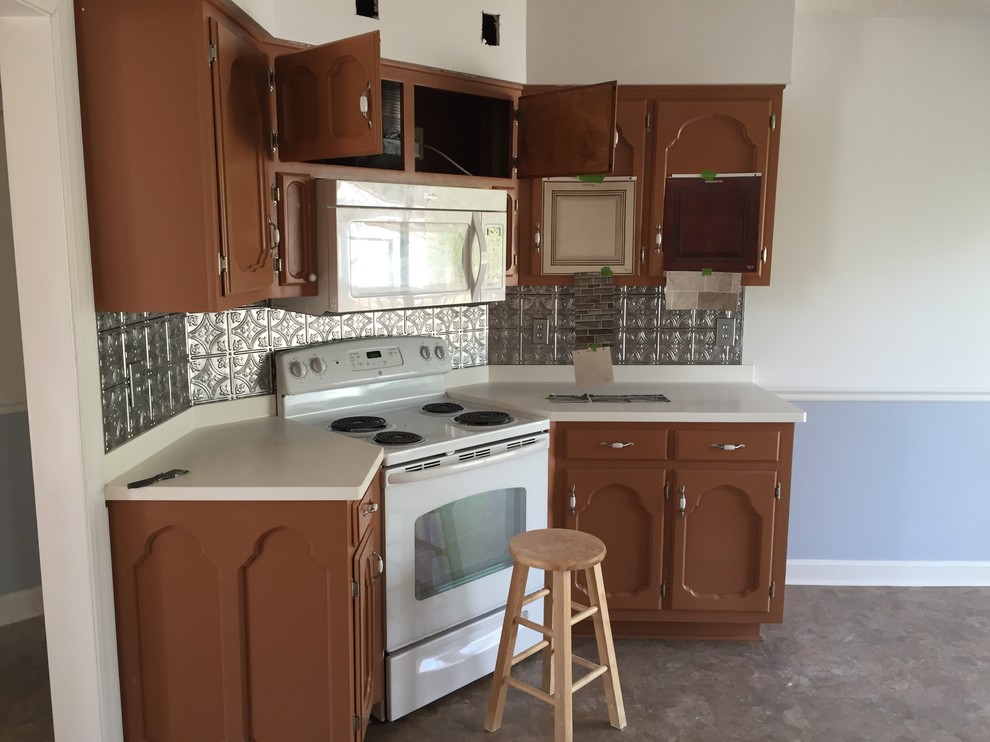 Mid-sized transitional galley vinyl floor enclosed kitchen photo with a farmhouse sink, raised-panel cabinets, beige cabinets, solid surface countertops, multicolored backsplash, stone tile backsplash, stainless steel appliances and no island