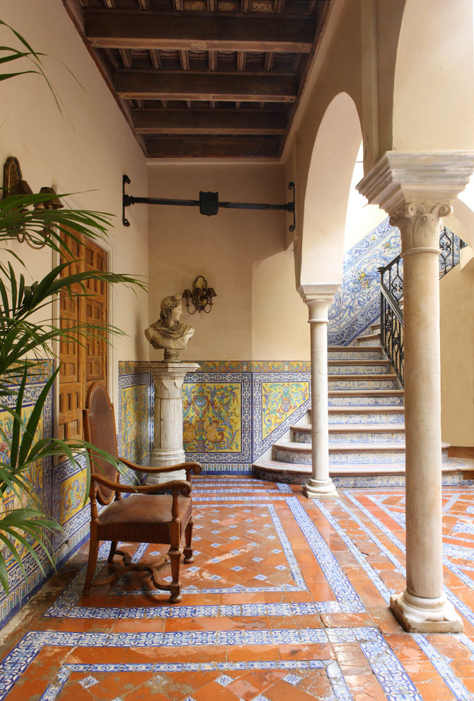 Large traditional courtyard patio in Seville with tile and a roof extension.