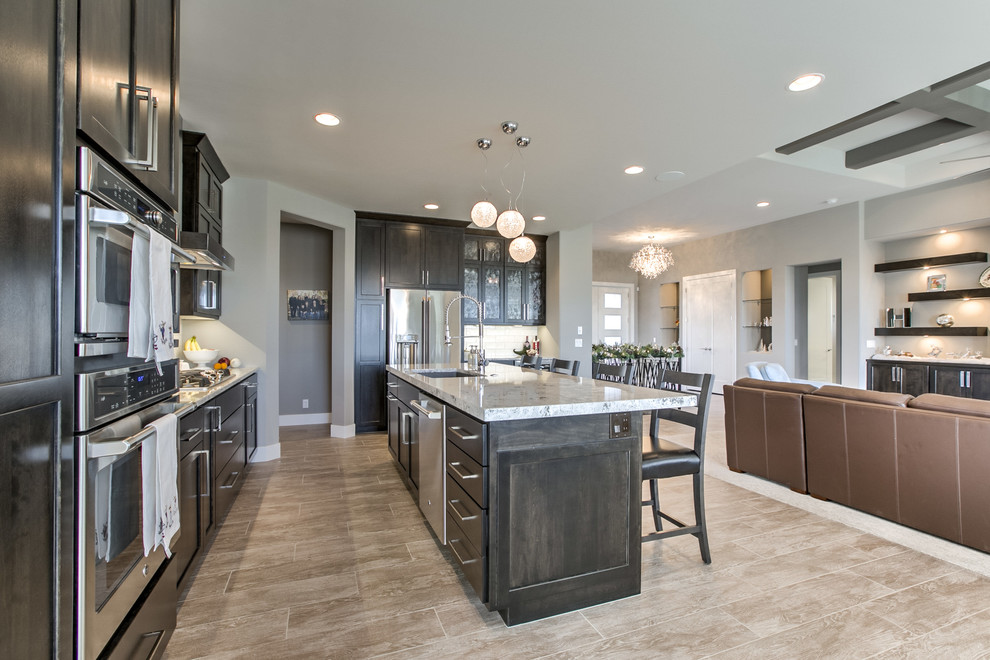 Open concept kitchen - transitional porcelain tile open concept kitchen idea in Omaha with an undermount sink, shaker cabinets, dark wood cabinets, granite countertops, white backsplash, mosaic tile backsplash, stainless steel appliances and an island