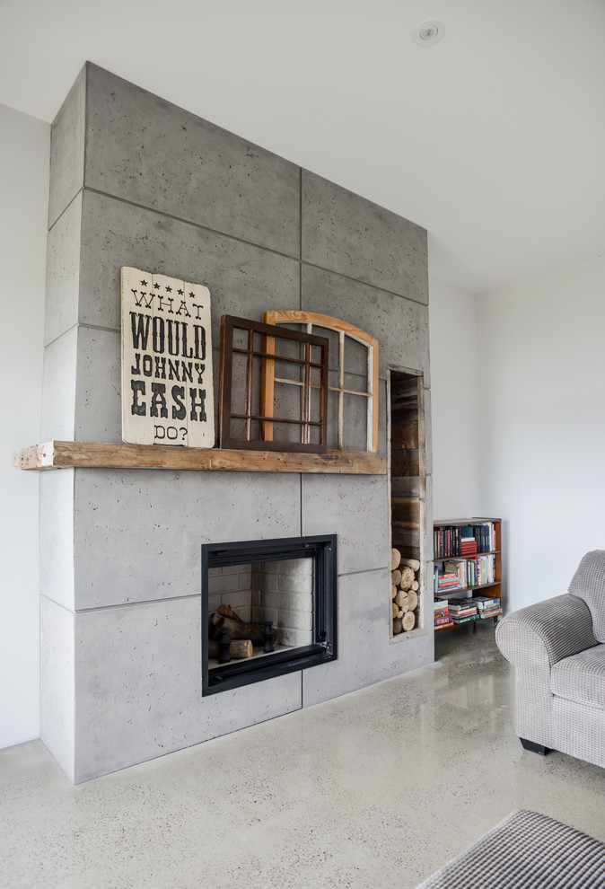 This is an example of a mid-sized contemporary open concept living room in Toronto with concrete floors, a standard fireplace, a concrete fireplace surround, a library, white walls, no tv and grey floor.