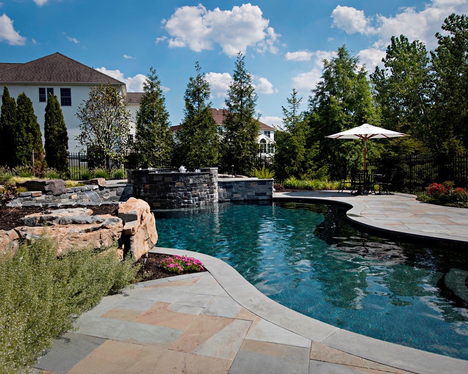 Inspiration for a large traditional backyard custom-shaped pool in Philadelphia with a hot tub and natural stone pavers.
