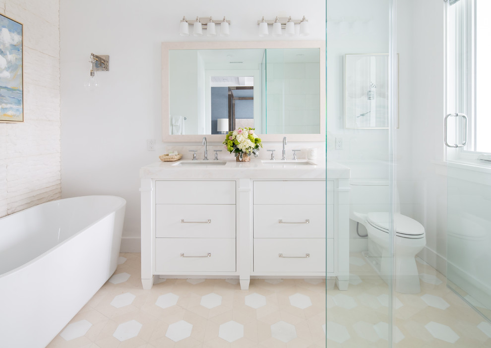 Beach style master bathroom in Orange County with white cabinets, a freestanding tub, a corner shower, white walls, an undermount sink, beige floor, white benchtops and flat-panel cabinets.