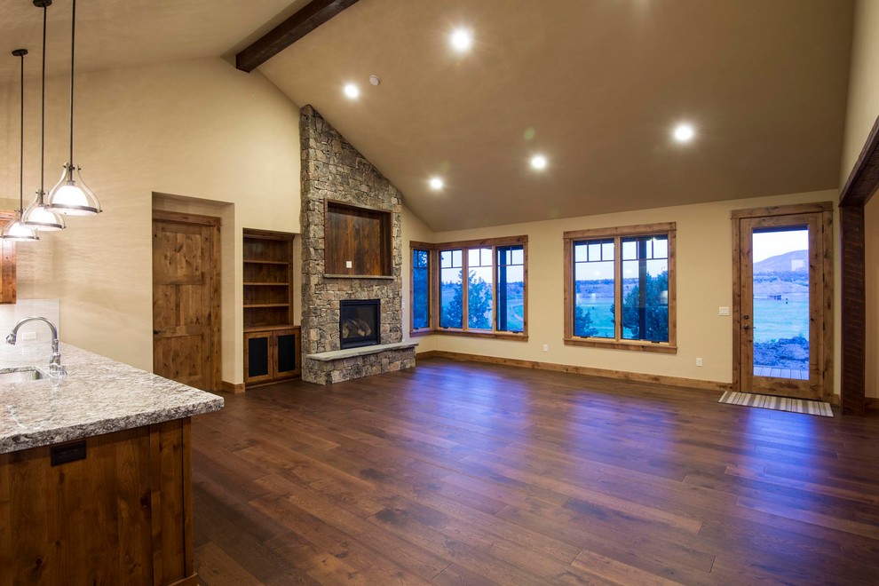 This is an example of a large country open concept living room in Other with medium hardwood floors, a standard fireplace, a stone fireplace surround and a built-in media wall.