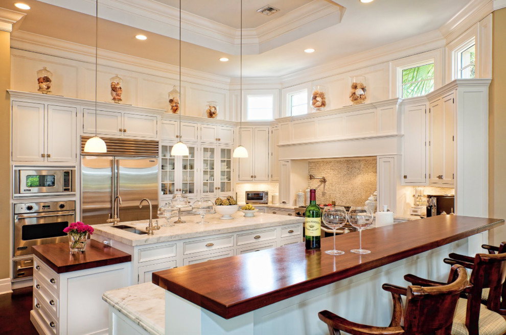 Inspiration for a timeless u-shaped kitchen remodel with an undermount sink, shaker cabinets, white cabinets, beige backsplash, mosaic tile backsplash, stainless steel appliances and an island