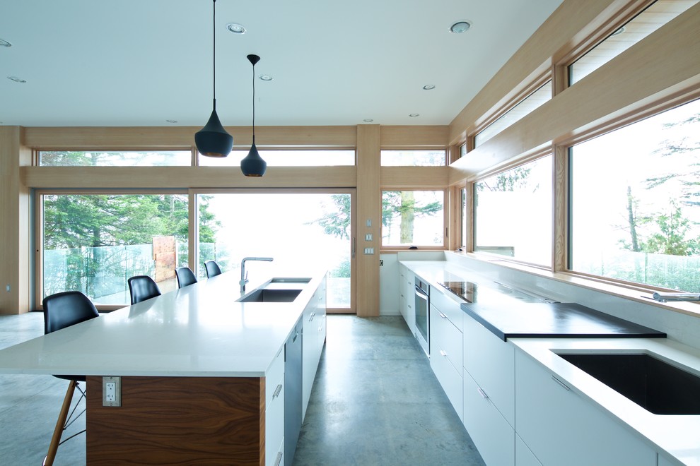 Mid-sized midcentury l-shaped open plan kitchen in Vancouver with an undermount sink, flat-panel cabinets, white cabinets, quartzite benchtops, white splashback, white appliances, concrete floors and with island.