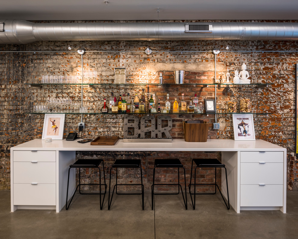 Photo of a mid-sized industrial single-wall wet bar in Cincinnati with no sink, flat-panel cabinets, white cabinets, brown splashback, brick splashback, concrete floors and grey floor.