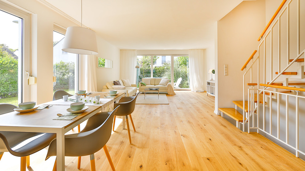 Wohnzimmer ohne Kamin With weißer Wandfarbe, gebeiztem Holzboden and braunem Boden in Essen