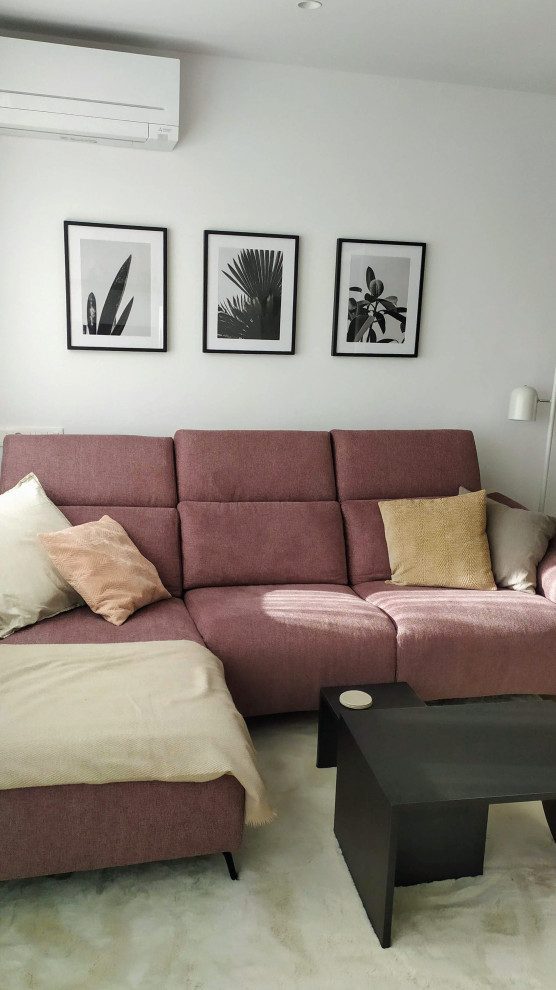 Mittelgroßes, Offenes Wohnzimmer mit weißer Wandfarbe, braunem Holzboden, Kamin, Kaminumrandung aus Metall und Eck-TV in Sonstige
