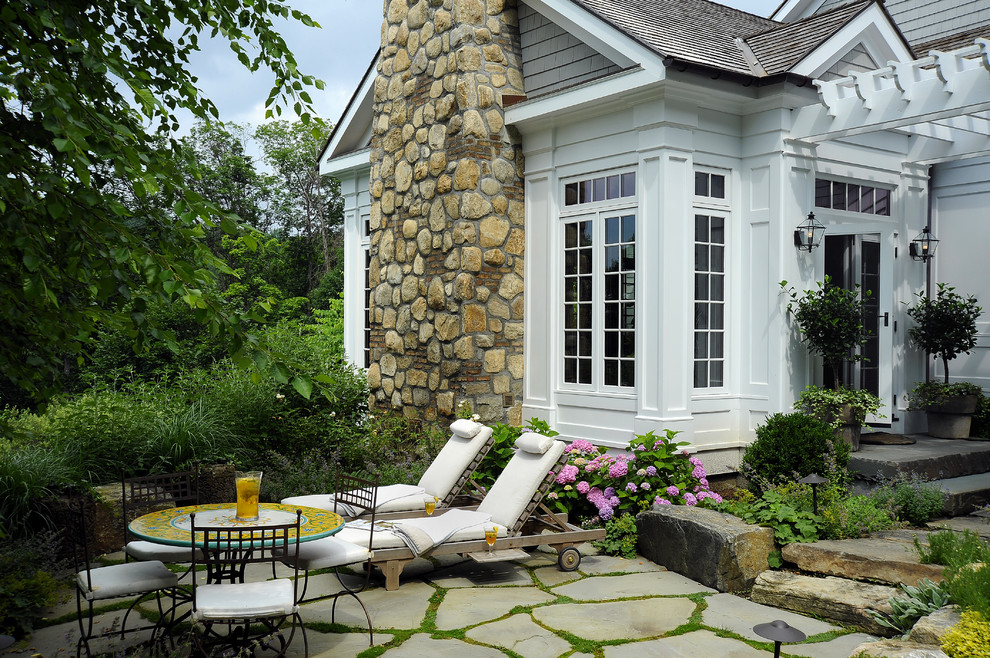 Large traditional backyard patio in New York with a pergola and natural stone pavers.