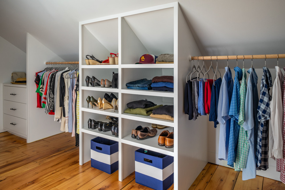 This is an example of an expansive country gender-neutral walk-in wardrobe in Boston with flat-panel cabinets and light hardwood floors.