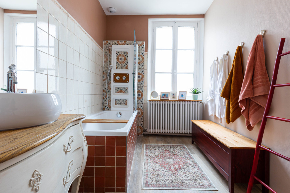 Exemple d'une salle de bain principale éclectique de taille moyenne avec un placard à porte affleurante, des portes de placard beiges, une baignoire encastrée, un combiné douche/baignoire, WC suspendus, un carrelage blanc, un carrelage orange, un carrelage rouge, des carreaux de céramique, un mur rose, parquet foncé, une vasque, un plan de toilette en bois, un sol marron, une cabine de douche à porte battante, un plan de toilette marron, meuble double vasque et meuble-lavabo sur pied.