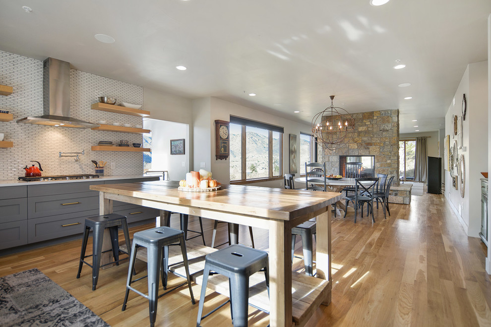 Mid-sized contemporary kitchen/dining combo in Denver with white walls, light hardwood floors, a two-sided fireplace, a stone fireplace surround and beige floor.