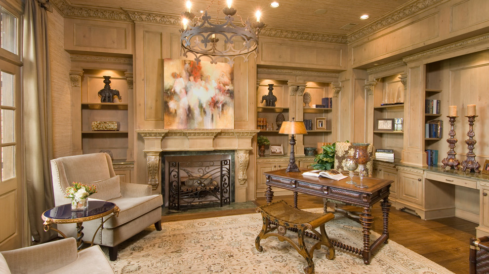 This is an example of a large traditional study room in Houston with medium hardwood floors, a standard fireplace, a wood fireplace surround and a freestanding desk.