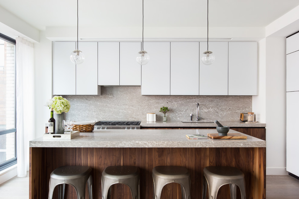 Photo of a contemporary kitchen in New York with an undermount sink, flat-panel cabinets, white cabinets, multi-coloured splashback, stainless steel appliances, with island and multi-coloured benchtop.