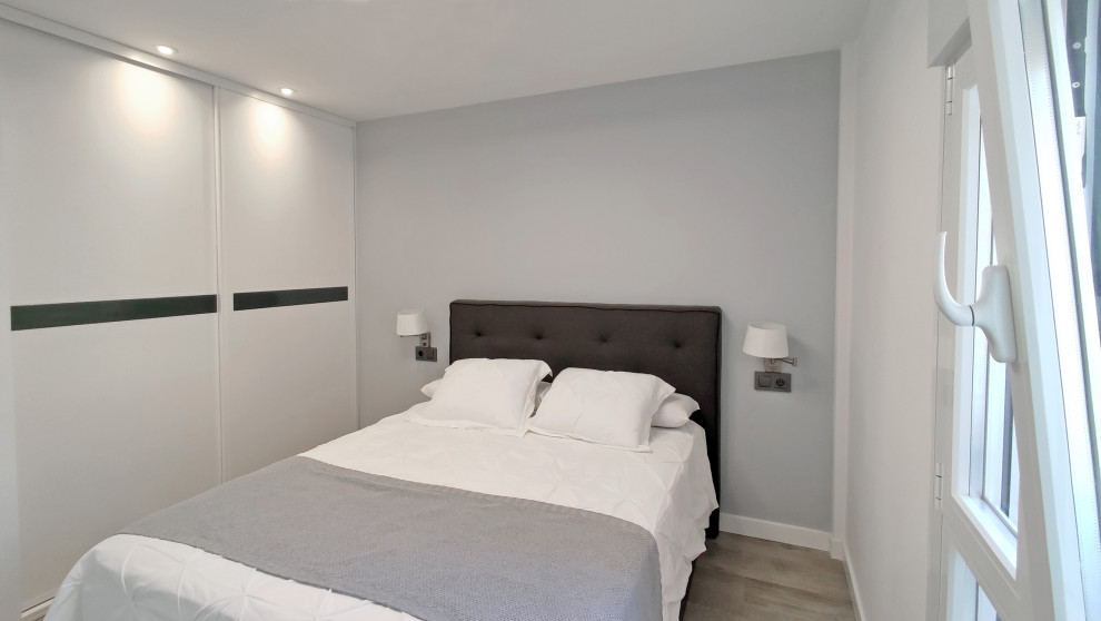 Diseño de dormitorio principal moderno grande con paredes blancas y suelo laminado