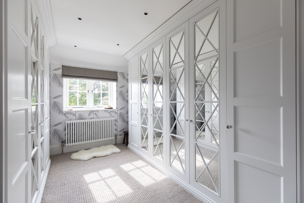 Inspiration for a transitional gender-neutral walk-in wardrobe in Dorset with recessed-panel cabinets, white cabinets, carpet and beige floor.