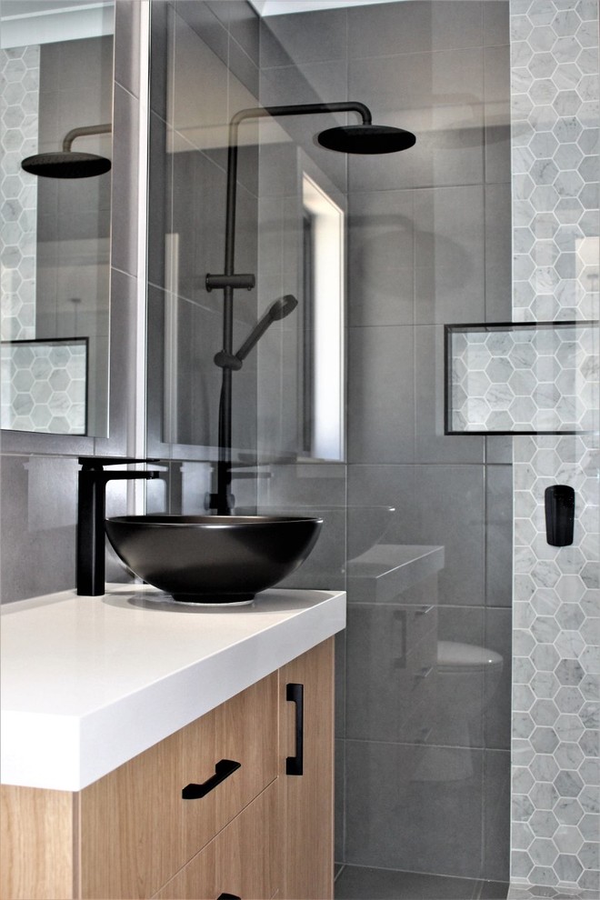 This is an example of a mid-sized contemporary master bathroom in Other with flat-panel cabinets, an open shower, ceramic tile, ceramic floors, a vessel sink, engineered quartz benchtops, an open shower, white benchtops, light wood cabinets, gray tile, grey walls and grey floor.