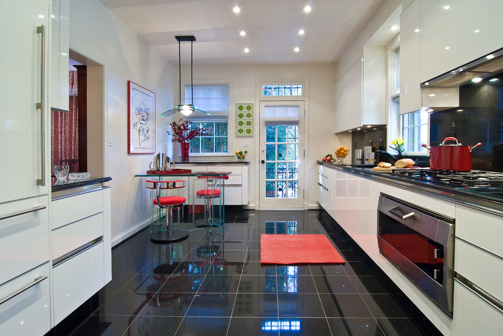 Design ideas for a mid-sized modern galley eat-in kitchen in DC Metro with flat-panel cabinets, white cabinets, an undermount sink, black splashback, stone slab splashback, stainless steel appliances, marble floors, black floor, with island, granite benchtops and black benchtop.