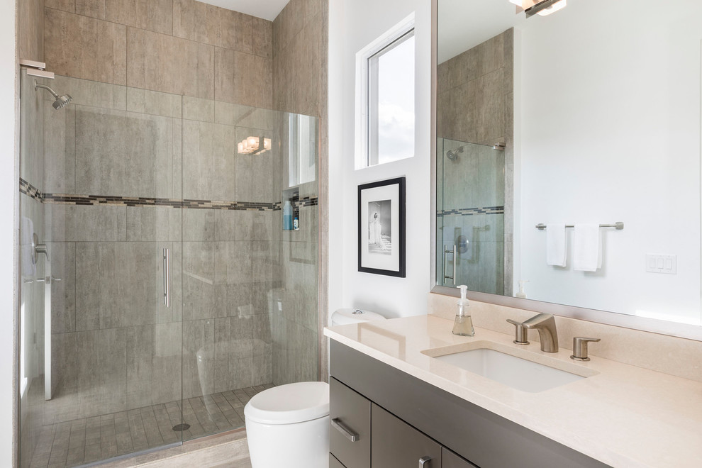 Inspiration for a mid-sized contemporary 3/4 bathroom in Orlando with flat-panel cabinets, grey cabinets, an alcove shower, a one-piece toilet, gray tile, porcelain tile, white walls, an undermount sink, engineered quartz benchtops and a hinged shower door.