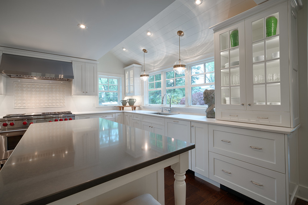 This is an example of a large transitional u-shaped eat-in kitchen in Philadelphia with an undermount sink, shaker cabinets, white cabinets, granite benchtops, white splashback, stone tile splashback, stainless steel appliances, medium hardwood floors, with island and brown floor.