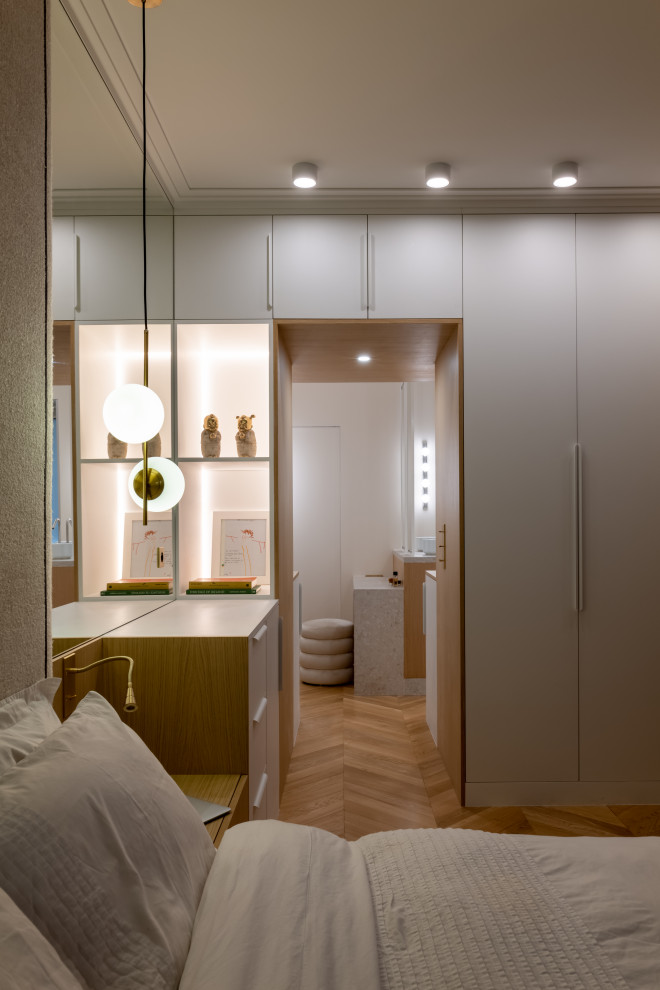 Aménagement d'une chambre parentale blanche et bois contemporaine de taille moyenne avec un mur blanc, parquet clair, un sol marron, du papier peint et dressing.
