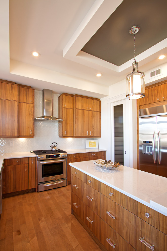 Inspiration for a large modern l-shaped medium tone wood floor eat-in kitchen remodel with an undermount sink, flat-panel cabinets, medium tone wood cabinets, quartz countertops, white backsplash, ceramic backsplash, stainless steel appliances and an island