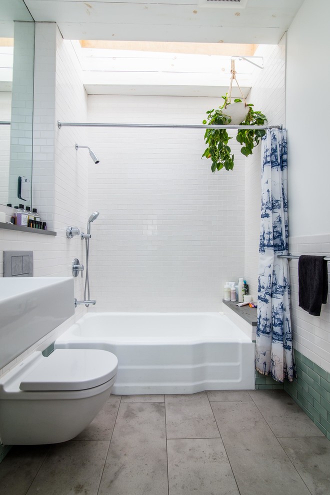 Photo of a mid-sized beach style master bathroom in New York with a wall-mount sink, an alcove tub, a shower/bathtub combo, a wall-mount toilet, white tile, ceramic tile, white walls, ceramic floors and a shower curtain.