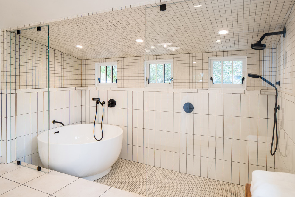 This is an example of a large transitional master wet room bathroom in Other with shaker cabinets, white cabinets, a japanese tub, a two-piece toilet, white tile, ceramic tile, white walls, limestone floors, an undermount sink, marble benchtops, beige floor, an open shower, white benchtops, an enclosed toilet, a double vanity, a built-in vanity, vaulted and decorative wall panelling.