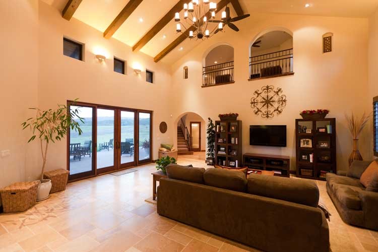 Design ideas for a mid-sized mediterranean open concept family room in San Luis Obispo with beige walls, travertine floors, no fireplace and a wall-mounted tv.