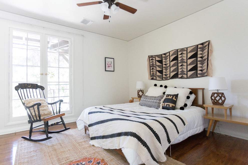 Photo of a mediterranean bedroom in Los Angeles with white walls, medium hardwood floors and brown floor.
