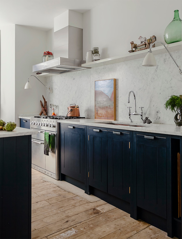 Design ideas for an eclectic kitchen in London with an undermount sink, raised-panel cabinets, black cabinets, white splashback, medium hardwood floors, with island and marble splashback.